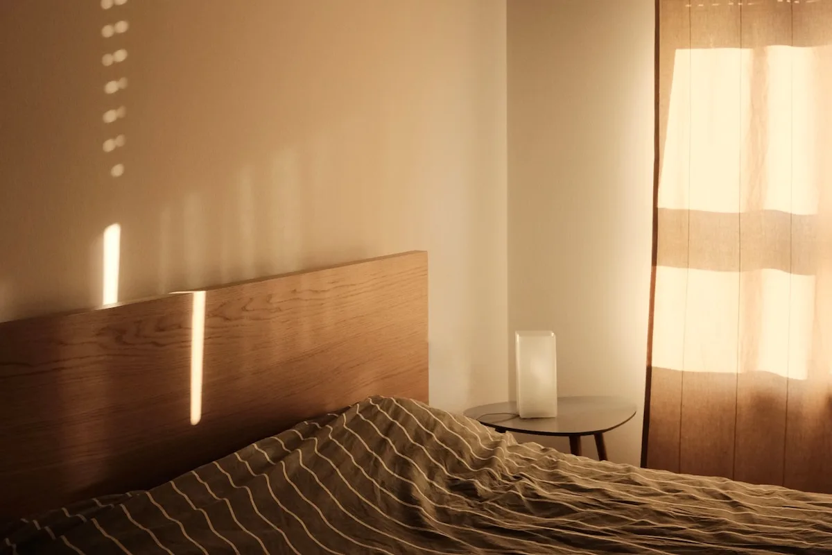 Sovrum i varmt kvällsljus med en liten lampa på nattduksbordet